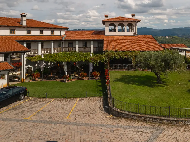 {"sl":"Pogled na dvori\u0161\u010de s parkiri\u0161\u010dem, zelenico in stavbo s terakotno streho","en":"","de":"","it":""}
