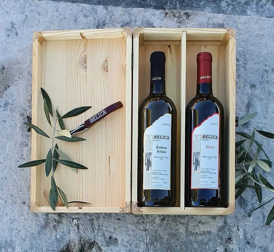 {"sl":"Olj\u010dne veje ob leseni \u0161katli z dvema steklenicama vina Belica, Rumena Rebula in Merlot.","en":"","de":"","it":""}